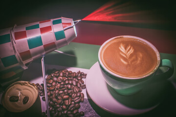 Cup of latte with foam art beside coffee beans and retro rocket lamp casting red light