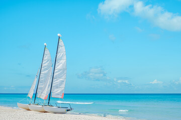 Sailboats anchored on a sandy beach under a clear blue sky