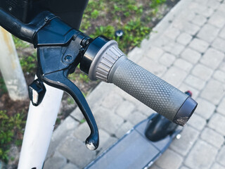 Close-up of an electric scooter handlebar on a sidewalk.
