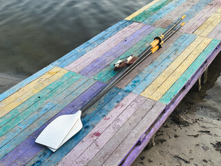 Colorful dock with oar by calm river, perfect for boating adventures.
