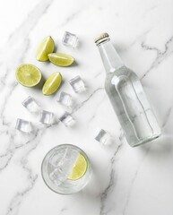 Glass bottle of water, ice cube and lime on a white marble background. Refreshing drink concept for summer. Hydration and healthy beverage idea.