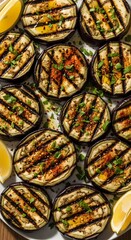 Slices of grilled eggplant seasoned with herbs and spices served with lemon wedges