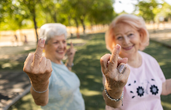 Senior women showing middle finger rude gesture smiling