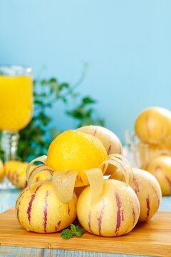 Fresh Yellow Striped Melons with Juice and Mint on Wooden Board
