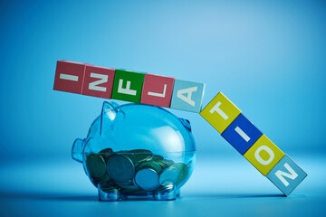 Piggy bank with inflation single word on cube blocks