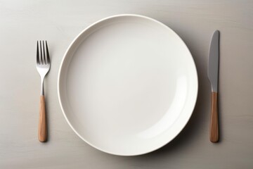 White ceramic plate with modern cutlery on minimal table setting from top view