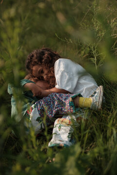 young kids snuggling in grass on sunny day
