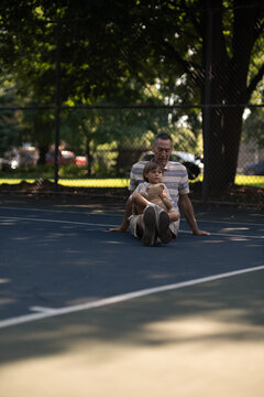 grandson sitting on grandpa's lap at the park on sunny day