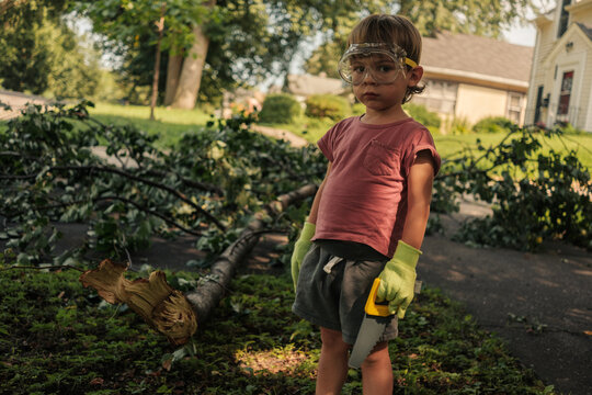 Young boy helping cut down tree outside on summer day