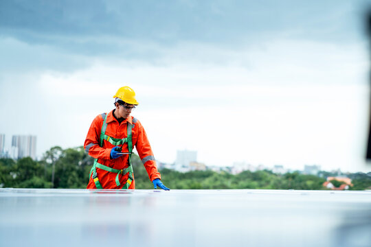 A man in an orange safety suit is working on a roof