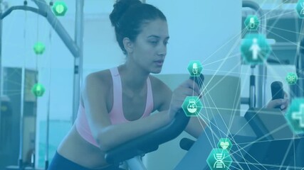 Woman tapping stationary bike console and generating green AR health metrics for fitness tracking - Powered by Adobe
