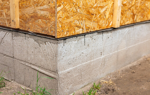 Plywood sheets on a concrete foundation, installation of OSB wall panels. Waterproofing of the house foundation. Close-up of the house foundation with waterproofing.