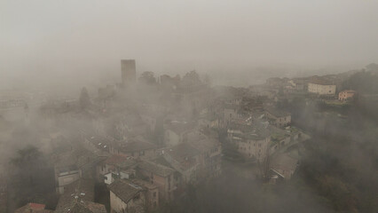Castell'Arquato medieval village shrouded in winter fog, Italy