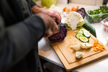 Close up of professional chef preparing ingredients for vegetarian meal in restaurant's kitchen. He is cutting cabbage.