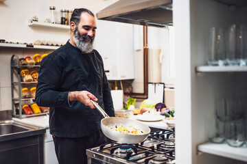 Portrait of professional chef who is working in restaurant's kitchen. He is preparing a meal.