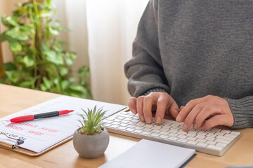 Person working from home, typing on a modern keyboard next to a clipboard with a 'work smarter, work harder' to-do list, emphasizing efficiency and productivity in achieving goals