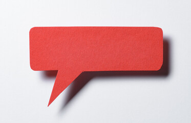 Red blank cut out paper speech bubble with shadow and copy space for text on white background, close-up flat lay top view conceptual backdrop