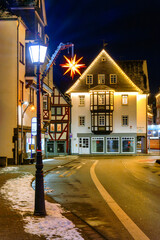 Half timber houses with stars and lights in Herborn, snowy street, wintry night scene