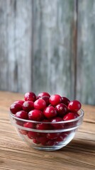 Bowl of Ripe Cranberries on Wooden Table: A clear glass bowl brimming with vibrant red cranberries rests on a rustic wooden table, offering a visual feast of color and texture.