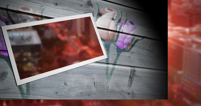 Animation of blurred cityscape on photo frame against floral design on wooden plank