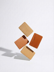 Minimalist levitating leather card holders in various tan shades on white.