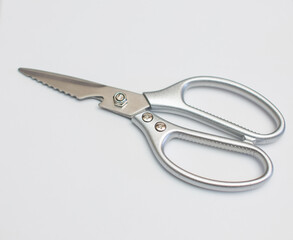 Stainless steel scissors are placed on a white surface.