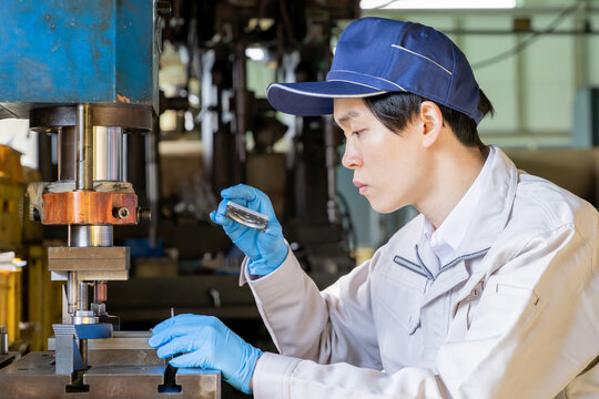 工場でプレス機械を操作する男性作業員