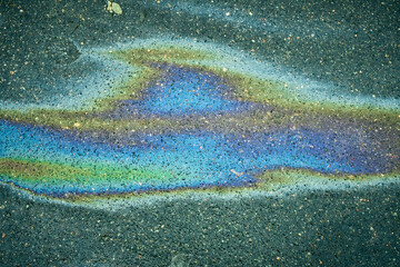 Oil Slick on Asphalt Shows Colorful Patterns in a Parking Lot Under Natural Light During the Day