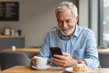 Senior man using smartphone in cafe