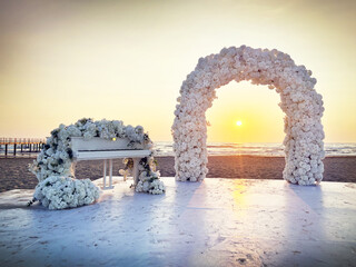 Romantic beach wedding ceremony with floral arch and piano at sunset