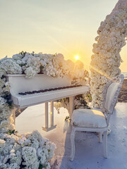 Romantic beach wedding ceremony with white piano and floral decorations at sunset