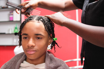 Smiling afro young man with nearly finished braids and one section left