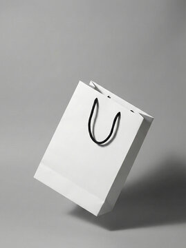 Minimalist white paper shopping bag with black handles floating in mid-air against a grey background.
