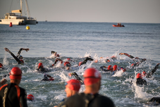 Swimmers compete in open water swimming event during the morning near a yacht in the ocean