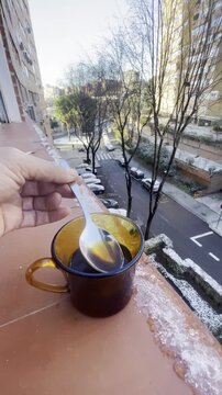 Taza de caf&eacute; caliente en d&iacute;a de nieve, fr&iacute;o y hielo removiendo y dando vueltas con cuchara en repisa de ventana