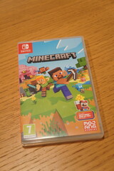Fototapeta premium Minecraft Nintendo Switch game case featuring iconic characters and blocky landscapes