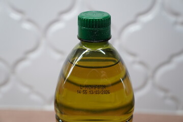 Close-up of a green cap on a clear plastic bottle filled with golden olive oil