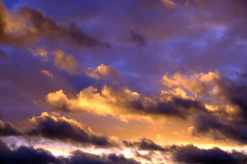 Obraz premium Dramatic Sunset Sky with Vibrant Purple and Golden Yellow Cumulus Clouds at Twilight