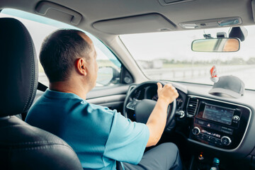 A middle-aged Caucasian man with short hair drives a car on a highway. He appears focused and relaxed, enjoying the journey.