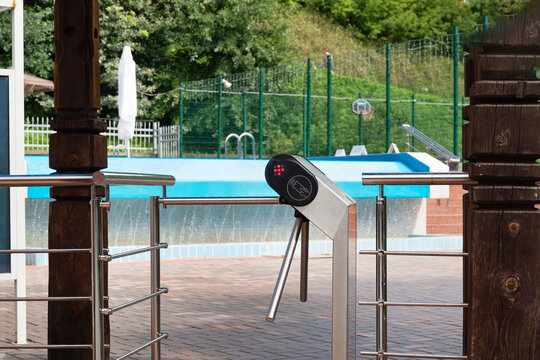 Entrance turnstile gate at swimming pool area on a sunny day.