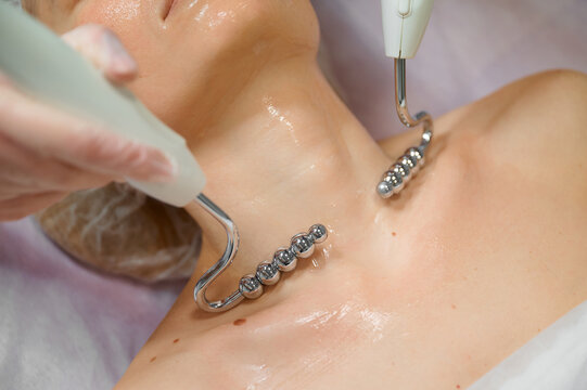 Woman receiving microcurrent treatment on neck in spa