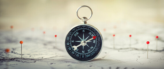 Compass  and location marking with a pin on routes on world map. Adventure, discovery, navigation, geography and travel theme concept background. Macro photo. Very shallow focus. © Tryfonov