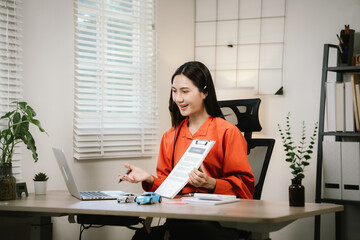 A young Asian businesswoman is holding a miniature car model, symbolizing auto insurance planning, vehicle financing, or automotive consulting in a modern office setting.