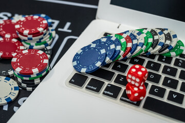 Stack of colorful poker chips near laptop keyboard representing online gambling, casino and poker games