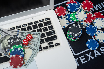 Laptop with poker chips, dice and dollars representing casino gaming, online betting and financial fortune