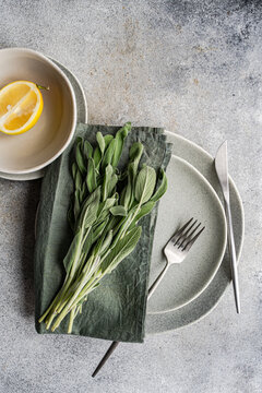 Overhead view of a place setting with fresh sage leaves and half a lemon