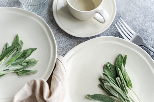 Overhead view of two place settings with fresh sage leaves