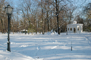 A white wooden pavilion known as the Echo Pavilion built in 1843 stands in the middle of a snowy forest in Maksimir Park during winter.