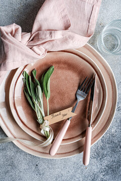 Overhead view of a rustic pink place setting with fresh sage leaves and a tag with the words Thank you