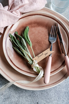 Overhead view of a rustic pink place setting with fresh sage leaves and a tag with the words Thank you